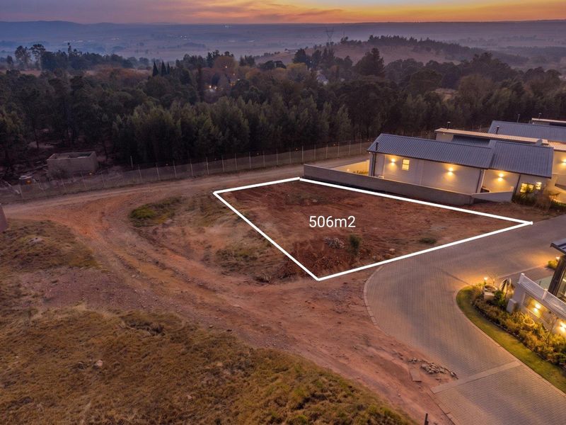 Aerial view of a 506m2 vacant residential plot situated in a developed estate with paved access and scenic landscape views.