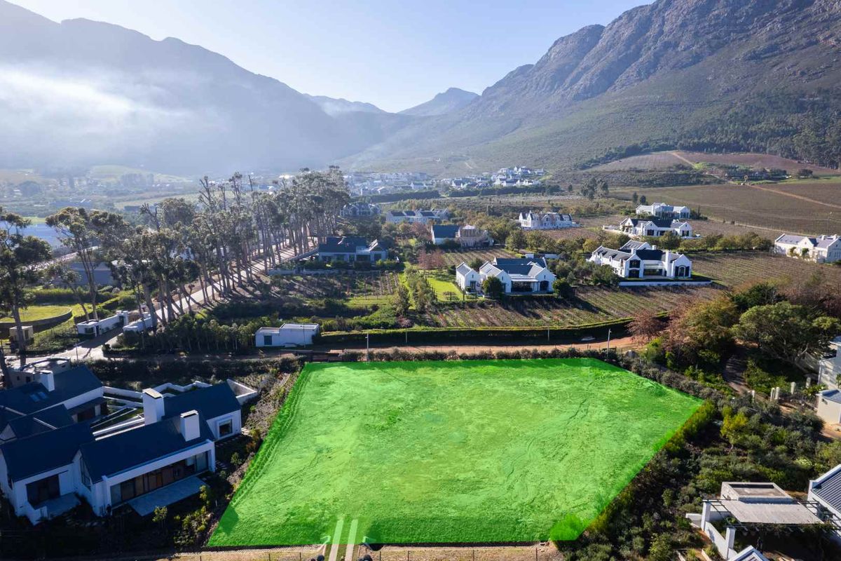An aerial view of a vacant residential plot situated in a scenic estate with mountain views and surrounding established homes.
