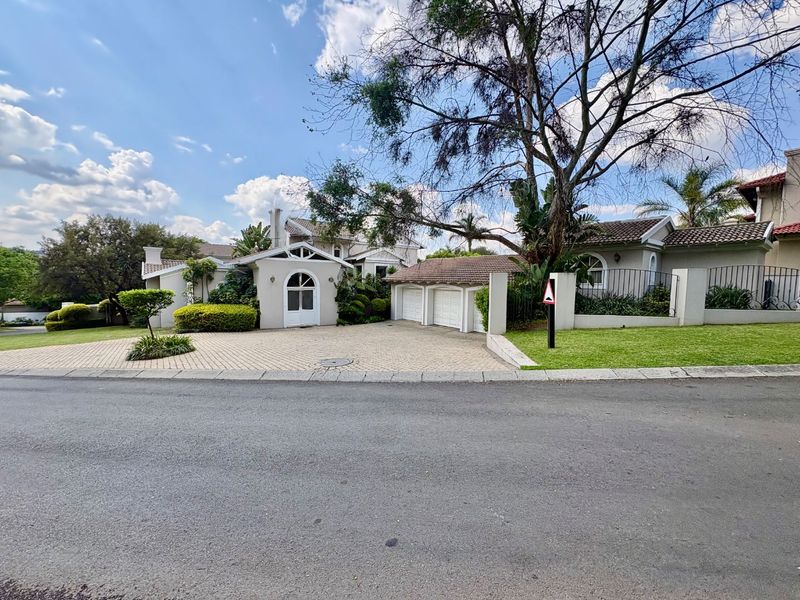 Front elevation of a well-maintained residence featuring a triple garage, paved driveway, and established garden with arched entrance detail.