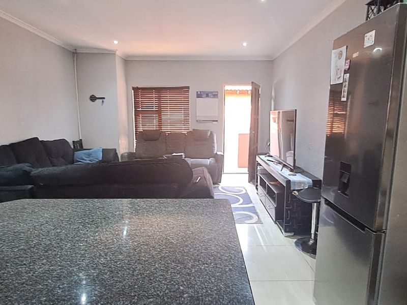 Open-plan living area featuring tiled flooring, recessed downlights, and a granite kitchen countertop, creating a functional and connected space.