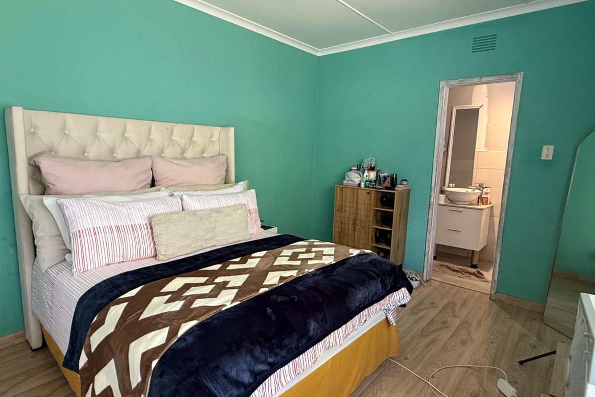 A bedroom featuring laminate flooring and direct access to an en-suite bathroom, with bright wall paint and a functional layout.