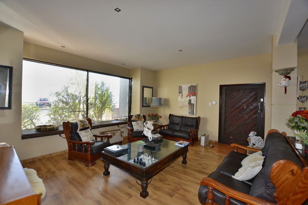 Spacious living room featuring large windows, recessed ceiling lighting, and wood-look flooring, providing a bright and comfortable area for relaxation.