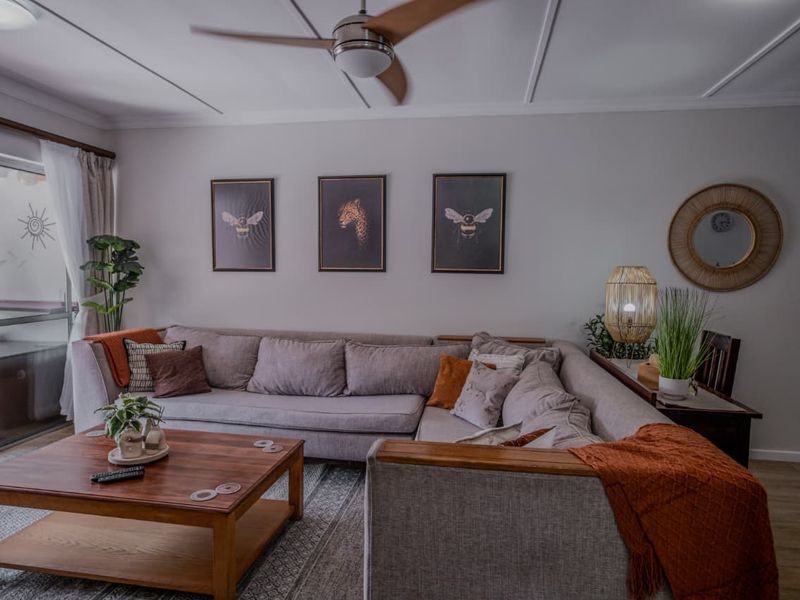 A comfortable living room featuring a ceiling fan, laminate flooring, and a large sliding glass door providing access to an outdoor area.