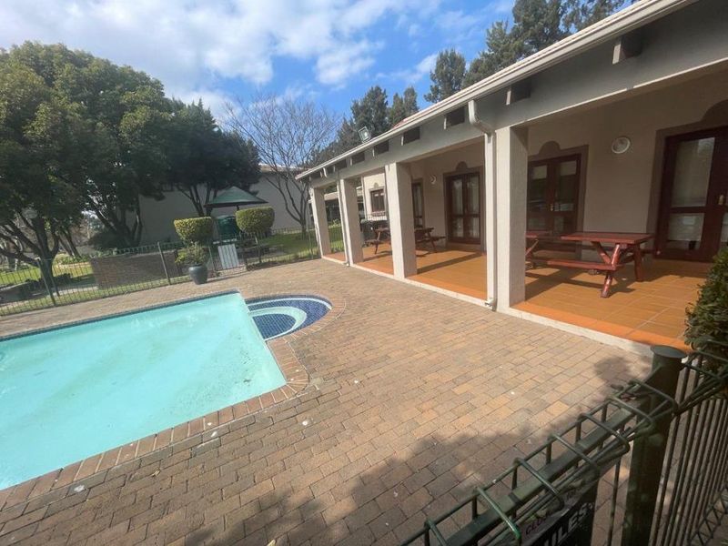 Outdoor pool area featuring a swimming pool, brick paved surround, and a covered patio with tiled flooring.