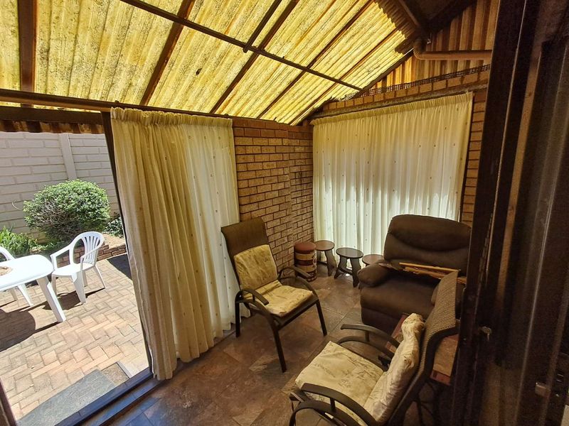 Enclosed patio area featuring exposed brick walls, tiled flooring, and a translucent corrugated roof, providing a sheltered outdoor living space.