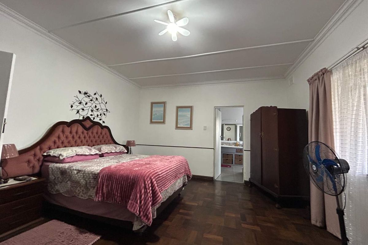 Spacious bedroom featuring classic parquet flooring, decorative ceiling coving, and direct access to an en-suite bathroom.