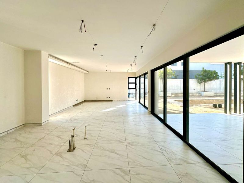 Spacious open-plan living area featuring large format marble-look floor tiles and expansive black aluminium sliding doors leading to the outdoor patio.