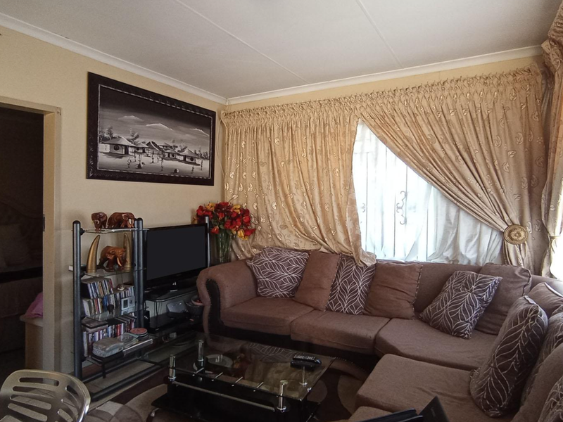 A cozy living room featuring neutral wall finishes, coved ceilings, and large window treatments, providing a comfortable and functional space.