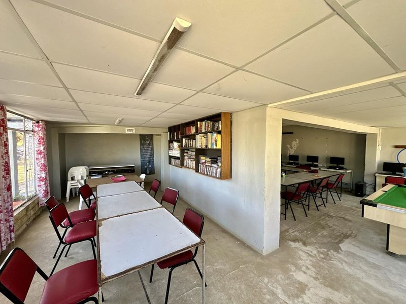 Spacious open-plan area featuring a suspended ceiling, built-in shelving, and concrete flooring, suitable for a multi-purpose utility or recreational space.