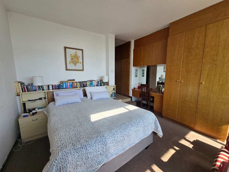 Spacious bedroom featuring extensive built-in wooden cabinetry, a integrated vanity unit, and neutral carpeting.