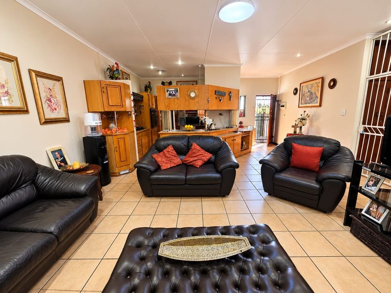 Open-plan living area featuring tiled flooring and a central kitchen with built-in cabinetry, providing a functional and connected space for daily living.