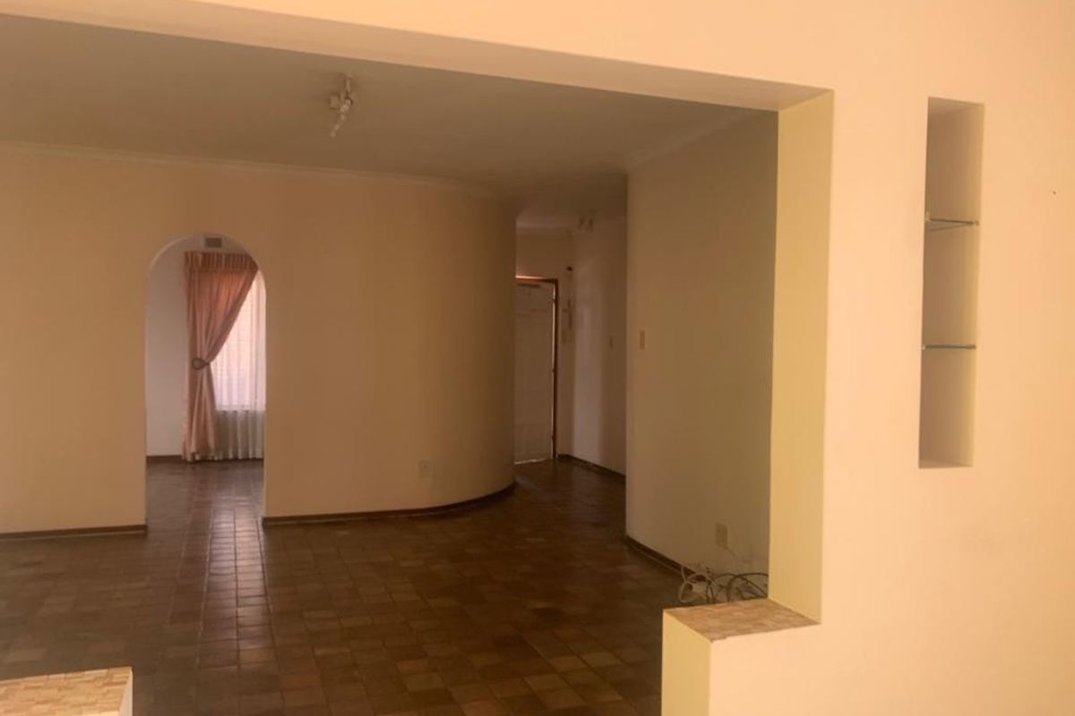 An empty living area featuring tiled flooring, an arched doorway, and a recessed wall niche, offering a blank canvas for interior design.