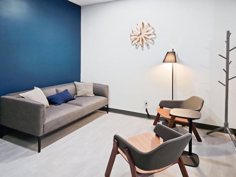 A modern office waiting area featuring a bold blue accent wall and neutral flooring, providing a professional and welcoming atmosphere.
