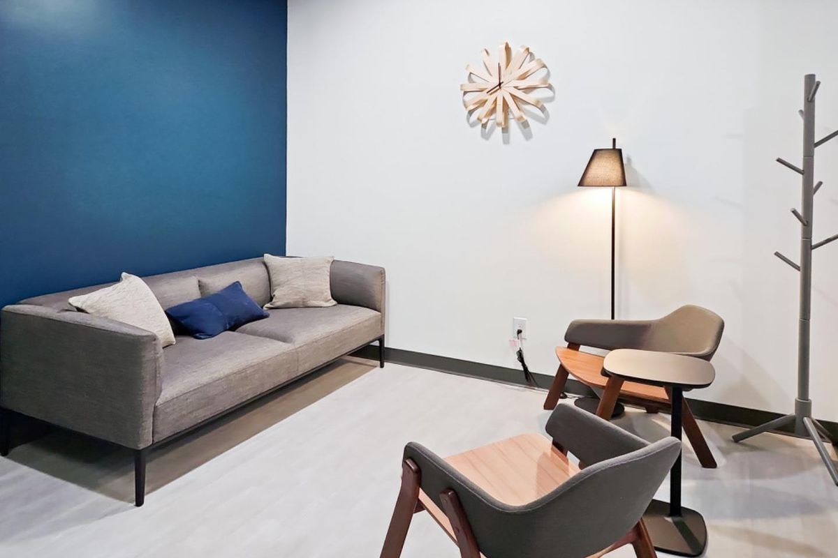 A modern office waiting area featuring a bold blue accent wall and neutral flooring, providing a professional and welcoming atmosphere.