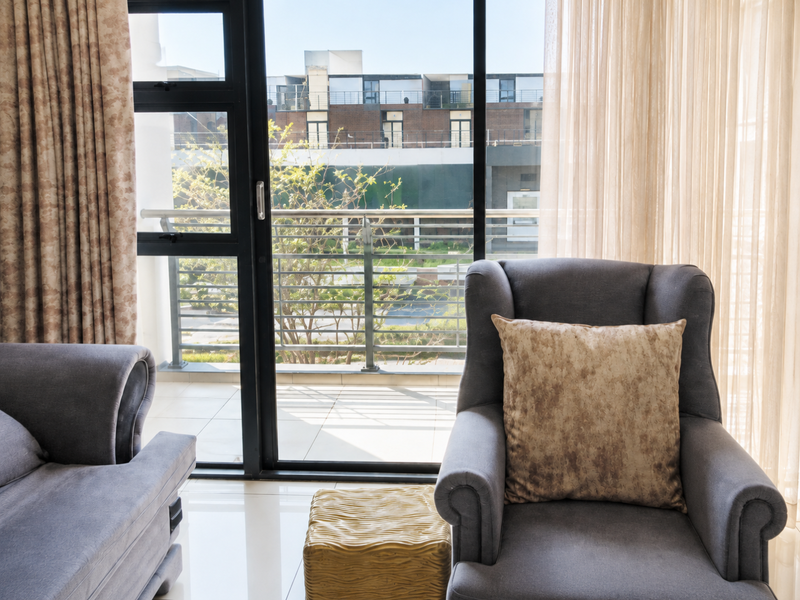 A bright living area featuring large sliding glass doors that open onto a private balcony with a metal railing.