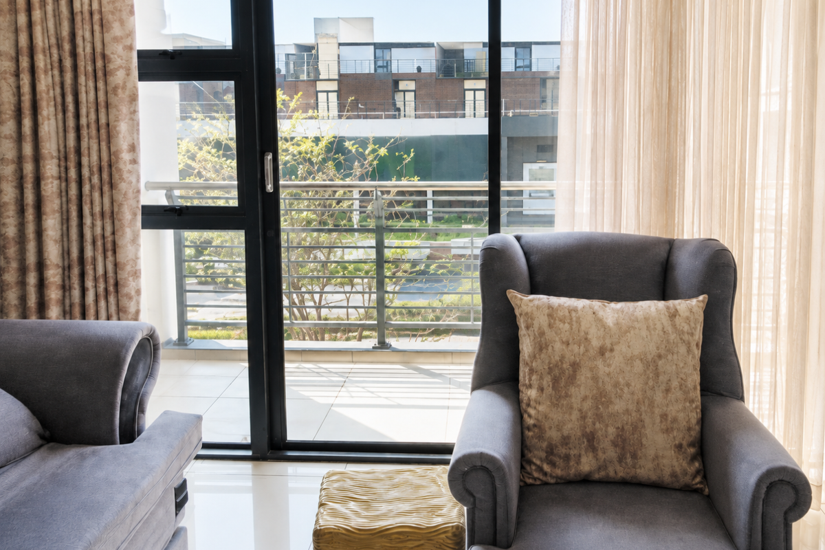 A bright living area featuring large sliding glass doors that open onto a private balcony with a metal railing.