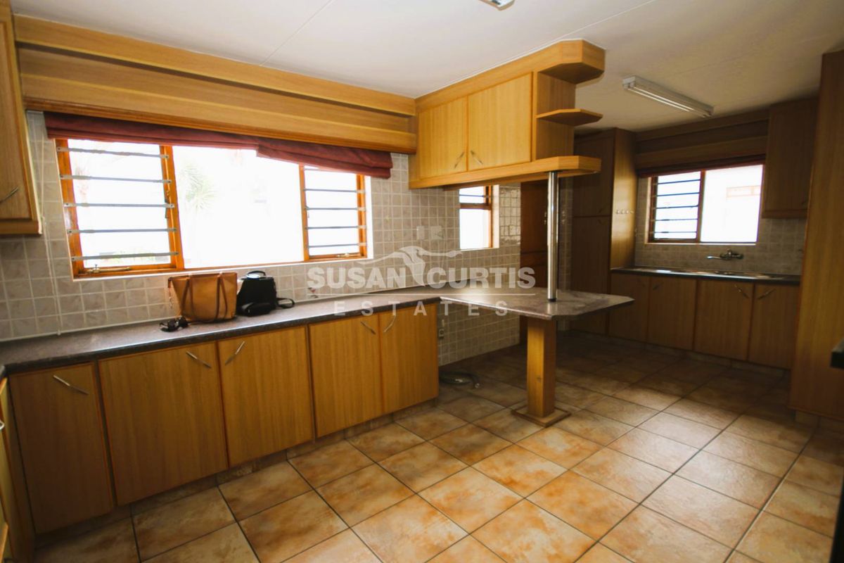A functional kitchen featuring laminate cabinetry, tiled backsplash, and a breakfast bar, offering a practical layout with ample counter space.