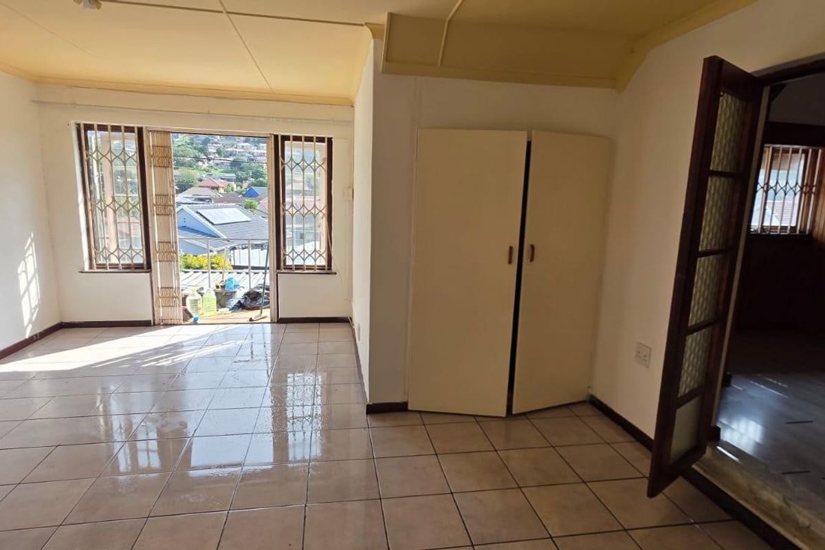 An empty living room featuring ceramic tiled flooring, built-in storage, and access to a balcony with security gates and window bars.