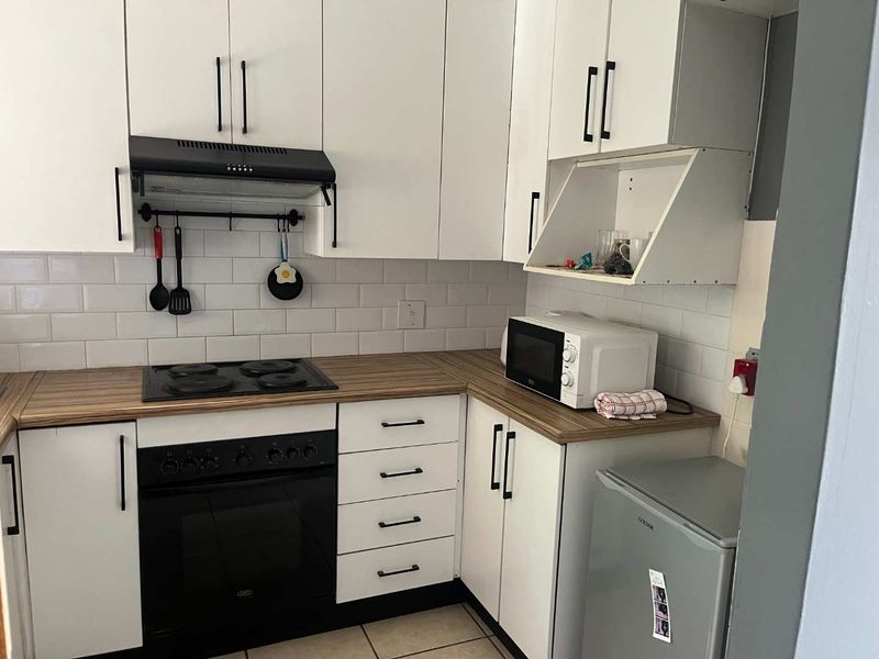 A functional kitchen featuring white cabinetry, a wood-look laminate countertop, subway tile backsplash, and integrated cooking appliances.