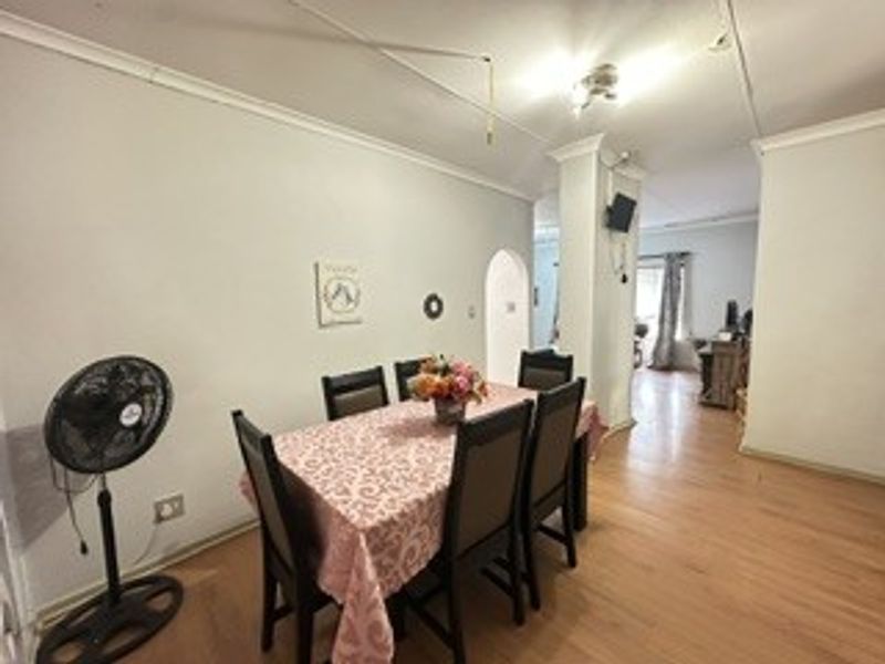 Dining area featuring laminate flooring and an archway leading to adjacent living space, with visible ceiling maintenance required.