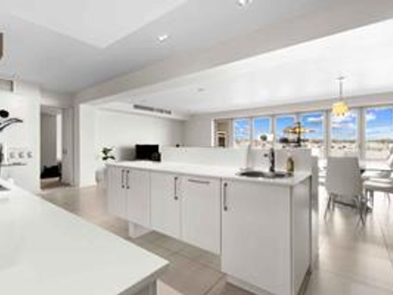 Modern open-plan living area featuring a sleek kitchen island, tiled flooring, and expansive windows providing ample natural light and views.