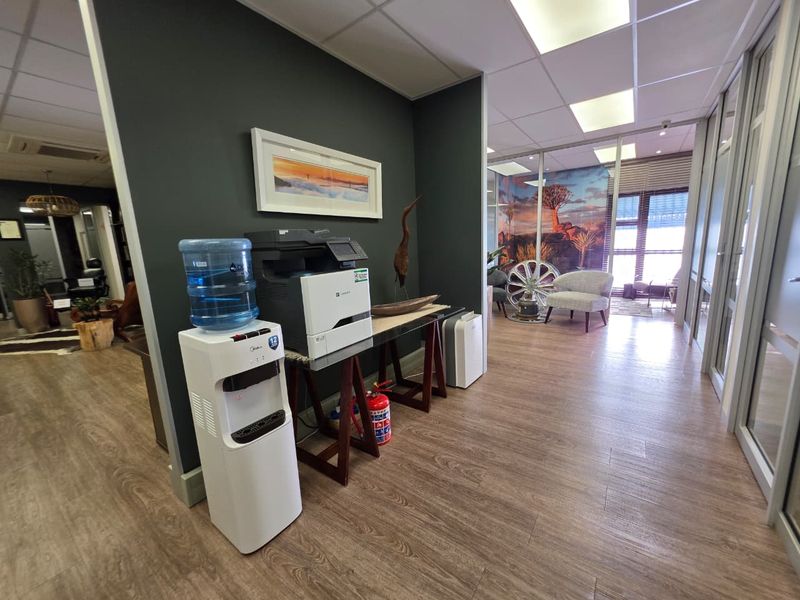 Modern office interior featuring laminate flooring, glass partition walls, and recessed lighting, creating a professional and well-maintained workspace environment.