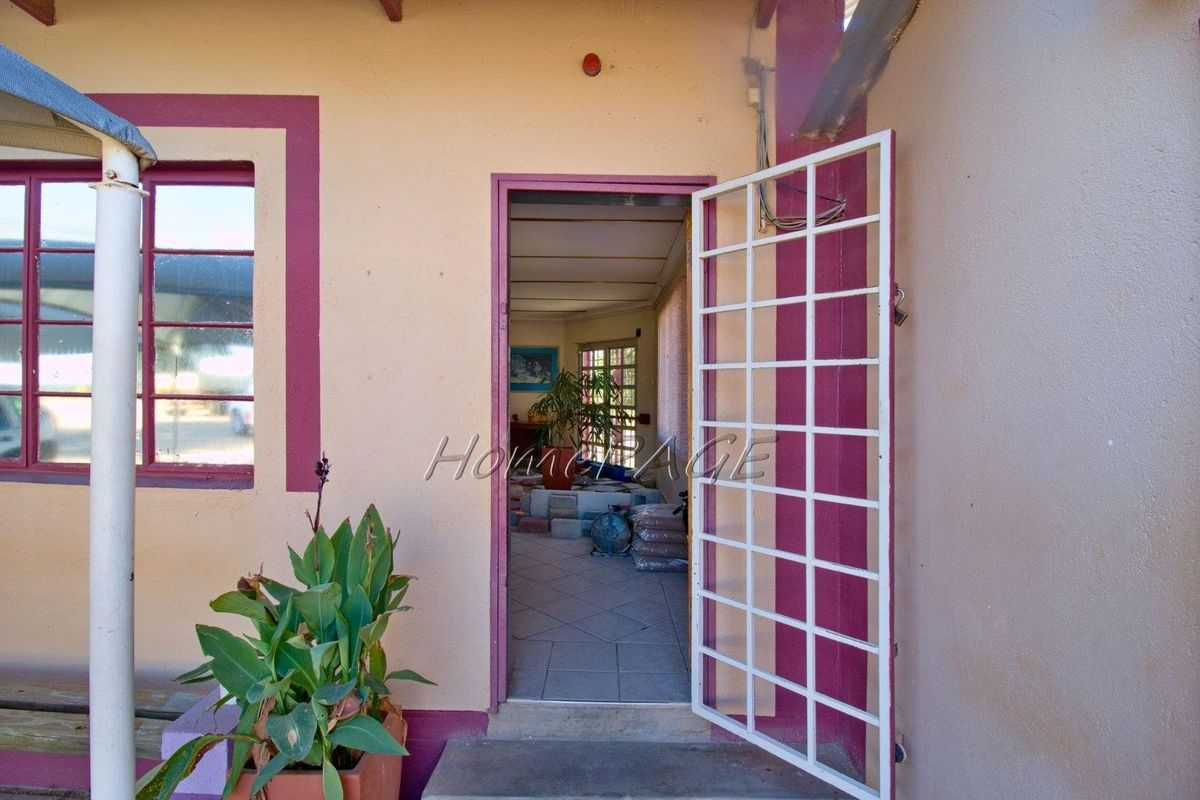 Exterior view of a building entrance featuring a security gate and tiled flooring, providing access to the interior space.