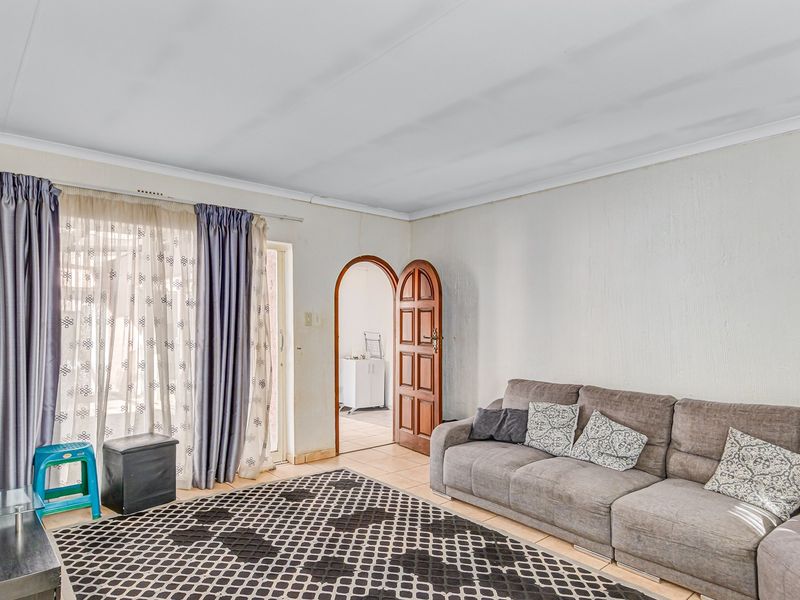 A living room featuring tiled flooring, an arched doorway, and a sliding glass door providing access to the exterior.
