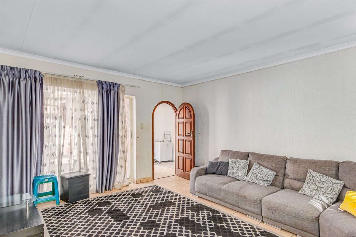 A living room featuring tiled flooring, an arched doorway, and a sliding glass door providing access to the exterior.