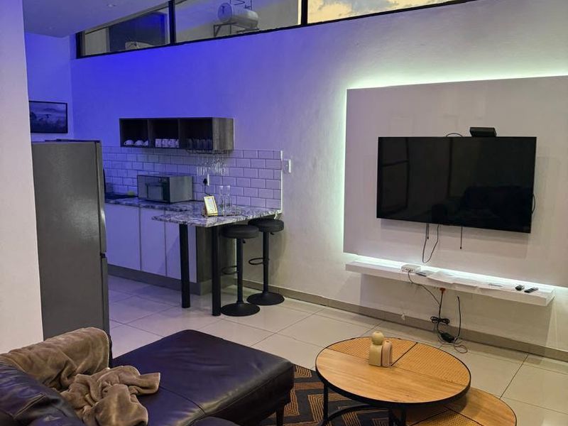 Modern open-plan living area featuring a sleek kitchen with subway tile backsplash, integrated lighting, and a floating media console under clerestory windows.