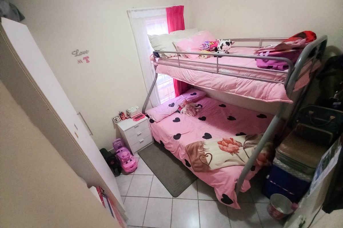 A compact bedroom featuring tiled flooring and a window with natural light, suitable for a child's room.
