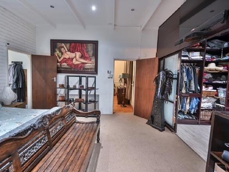 Spacious bedroom featuring an exposed brick wall, recessed ceiling lighting, and a large built-in wardrobe with open shelving.