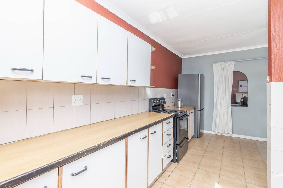 A functional kitchen featuring laminate countertops, tiled backsplash, and built-in cabinetry, offering a practical layout with potential for cosmetic updates.