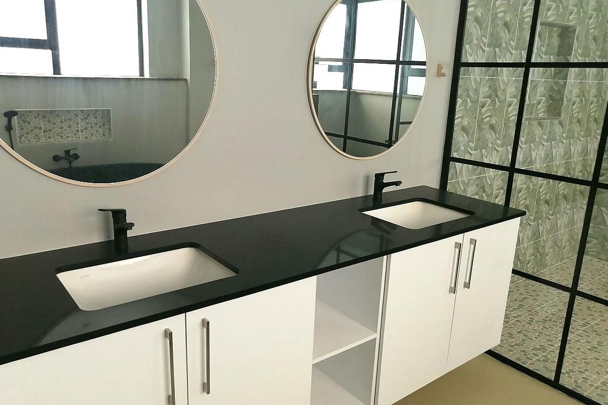 Modern bathroom featuring a double vanity with black stone countertop, dual undermount sinks, matte black faucets, and a walk-in shower with a black-framed glass screen.