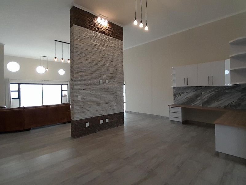 Spacious open-plan living area featuring a striking stone feature wall, modern cabinetry, and large sliding doors providing ample natural light.