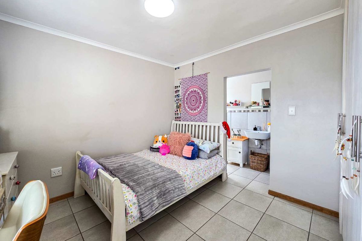 A bedroom featuring tiled flooring and direct access to an en-suite bathroom, providing a functional and well-lit living space.