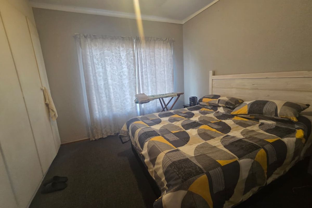 A standard bedroom featuring built-in cupboards and carpeted flooring, providing a functional and comfortable living space.