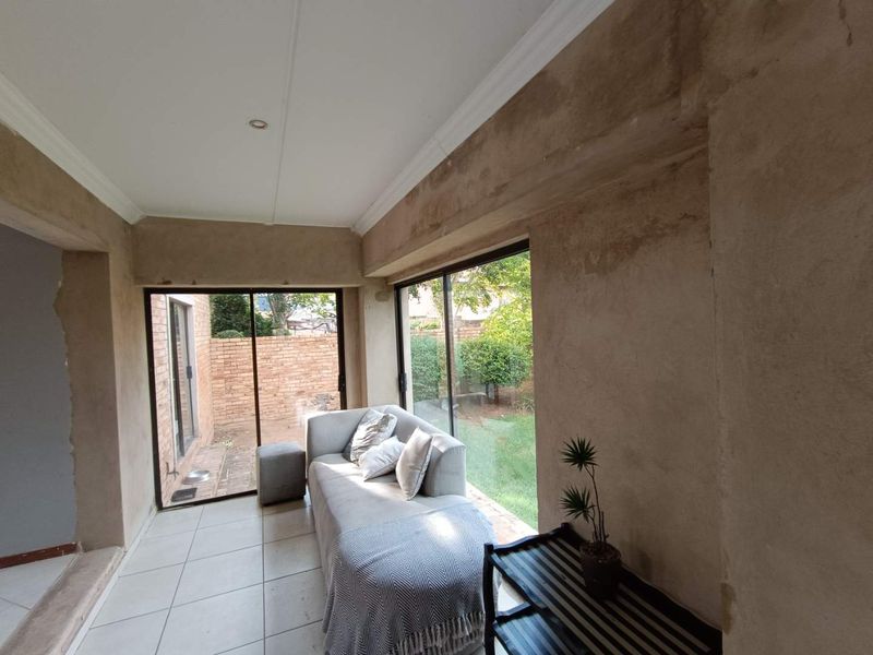 Enclosed patio area featuring large sliding glass doors, tiled flooring, and unfinished plaster walls, offering potential for a modern renovation.