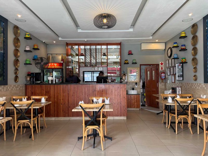 A well-maintained restaurant dining area featuring a wooden service counter, tiled flooring, and decorative wall-mounted shelving.