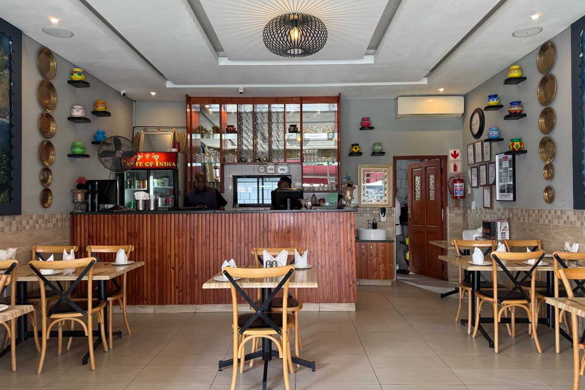 A well-maintained restaurant dining area featuring a wooden service counter, tiled flooring, and decorative wall-mounted shelving.