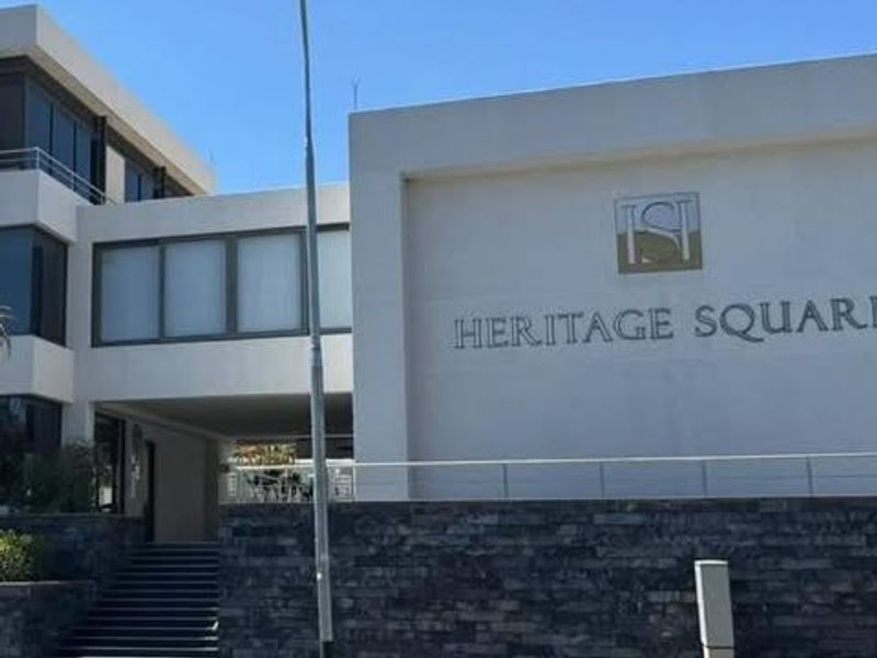Front facade of Heritage Square office building featuring modern stone cladding, concrete stairs, and prominent building signage.