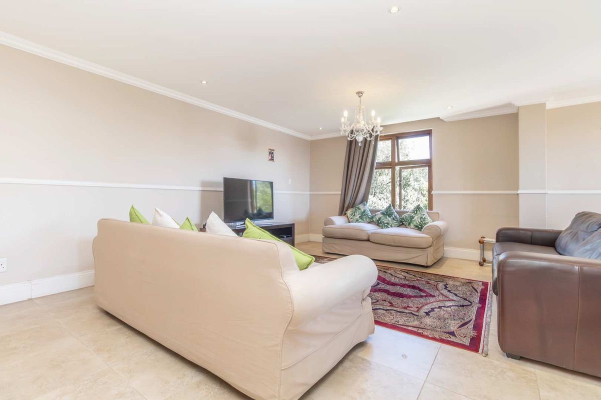 Spacious living room featuring neutral wall tones, crown molding, chair rail detailing, tiled flooring, and recessed lighting.