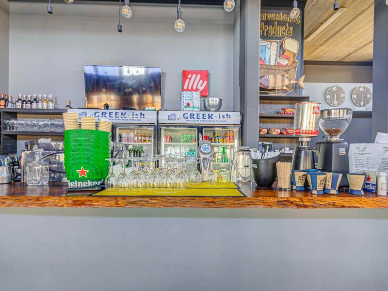 A well-equipped commercial bar area featuring a wooden counter, integrated refrigeration units, and built-in shelving for display and service.