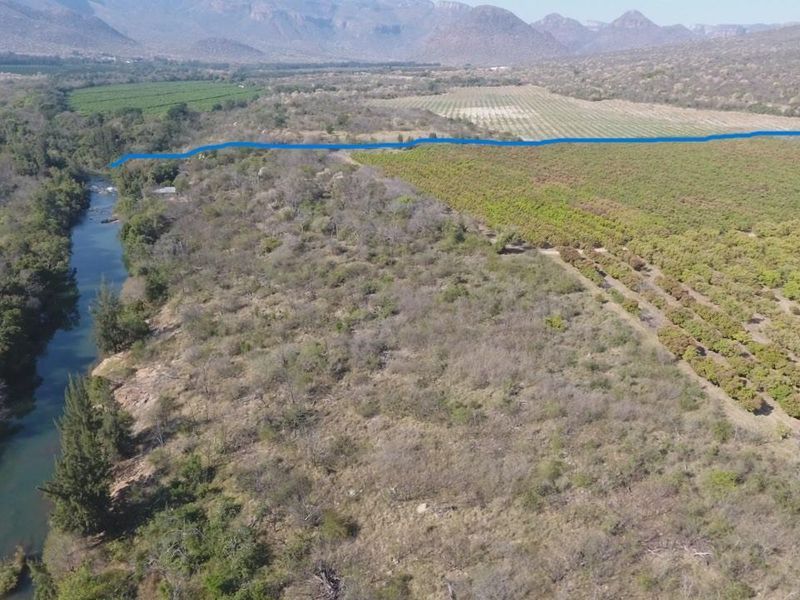 Aerial view of the farm property featuring extensive orchards, natural river frontage, and surrounding mountainous landscape.