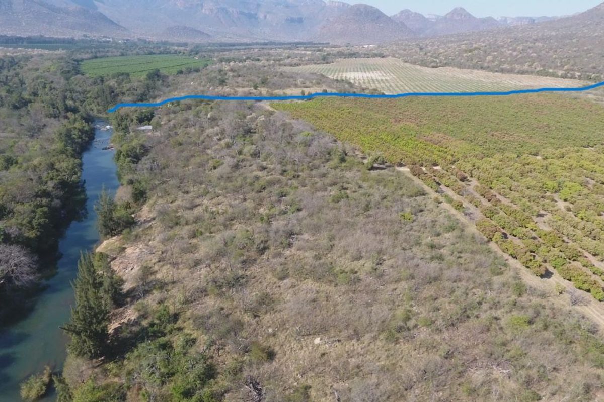 Aerial view of the farm property featuring extensive orchards, natural river frontage, and surrounding mountainous landscape.