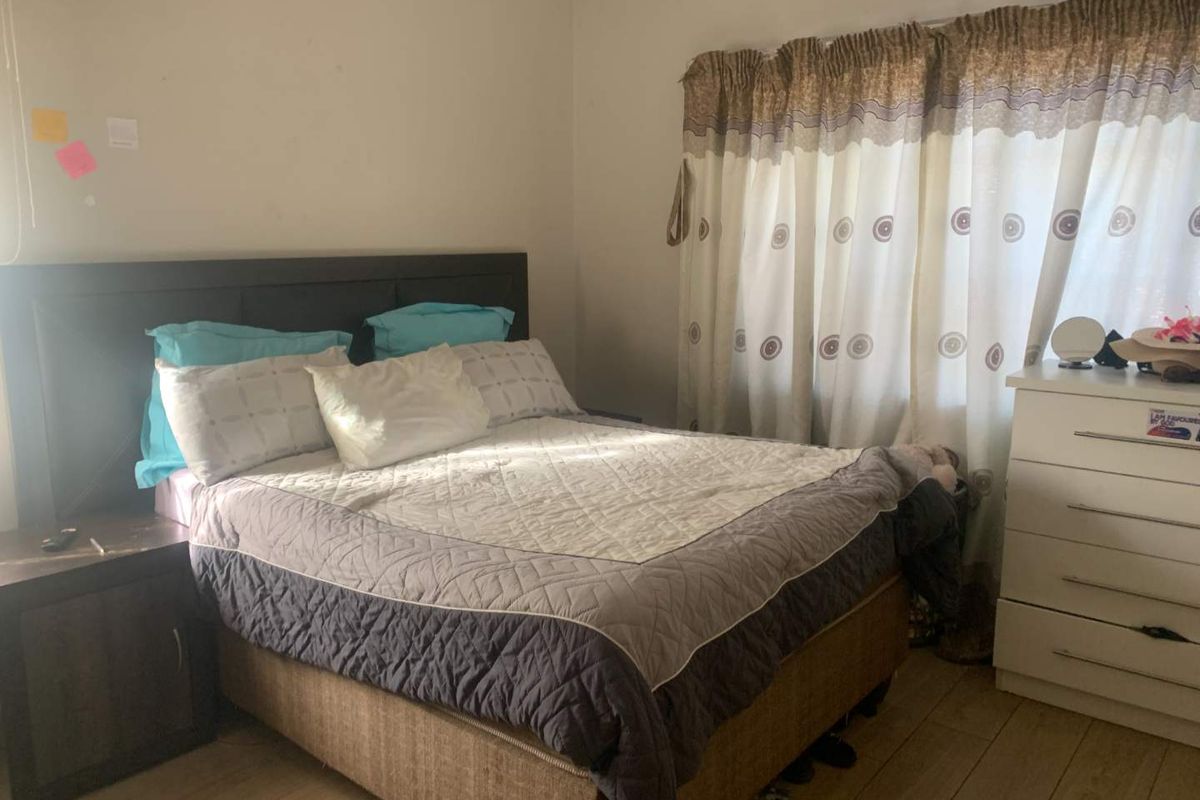 A standard bedroom featuring laminate flooring and window treatments, offering a functional space ready for personalization.