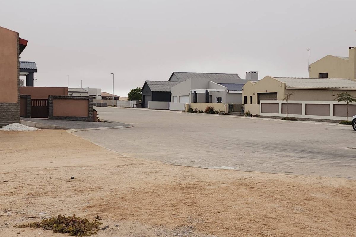 A view of the residential street showing paved road access and surrounding established boundary walls in a quiet neighborhood setting.