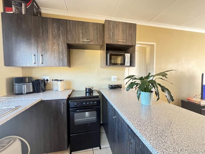 A functional kitchen featuring dark wood-look cabinetry, speckled laminate countertops, and a freestanding oven, providing a practical workspace for daily cooking.
