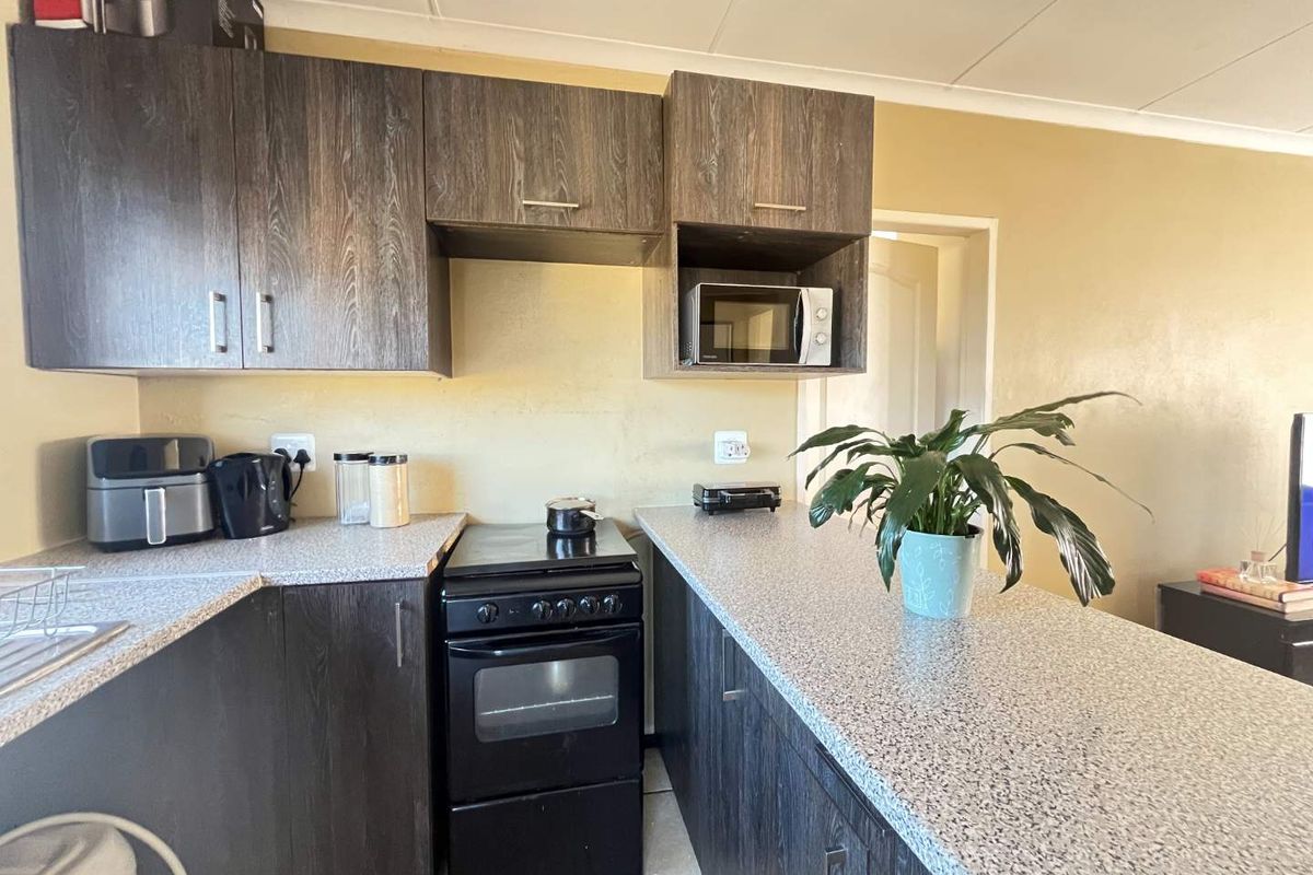 A functional kitchen featuring dark wood-look cabinetry, speckled laminate countertops, and a freestanding oven, providing a practical workspace for daily cooking.