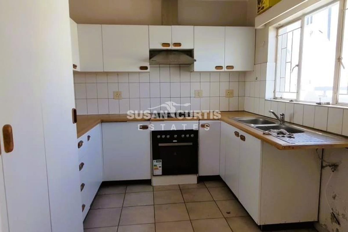 A functional kitchen featuring white cabinetry, laminate countertops, a built-in oven, and a double sink with a tiled backsplash.
